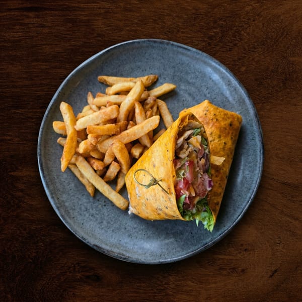 A chicken wrap with fresh vegetables and a side of golden french fries on a dark plate.